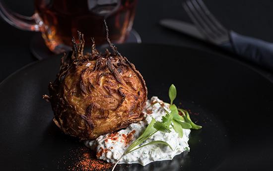 Knusprige italienische Vorspeise mit Kräuterdip und frischen Gewürzen auf schwarzem Teller